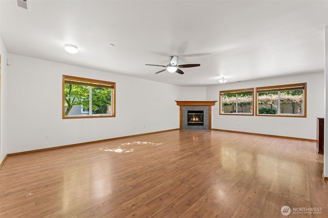 unfurnished living room with ceiling fan, light wood finished floors, a fireplace, and baseboards