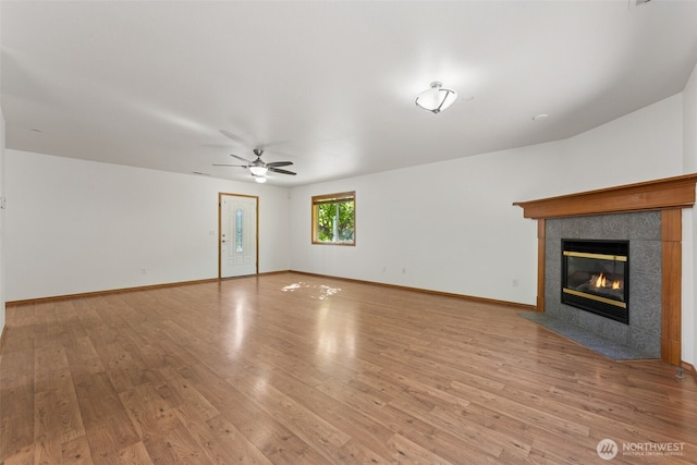 unfurnished living room featuring wood finished floors, ceiling fan, a fireplace, and baseboards