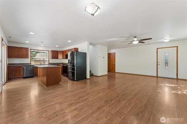 kitchen with fridge with ice dispenser, dishwasher, open floor plan, wood finished floors, and a kitchen island