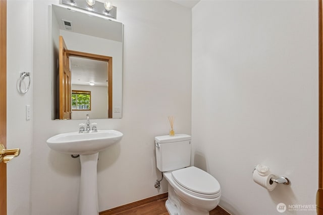 bathroom featuring toilet, wood finished floors, and a sink