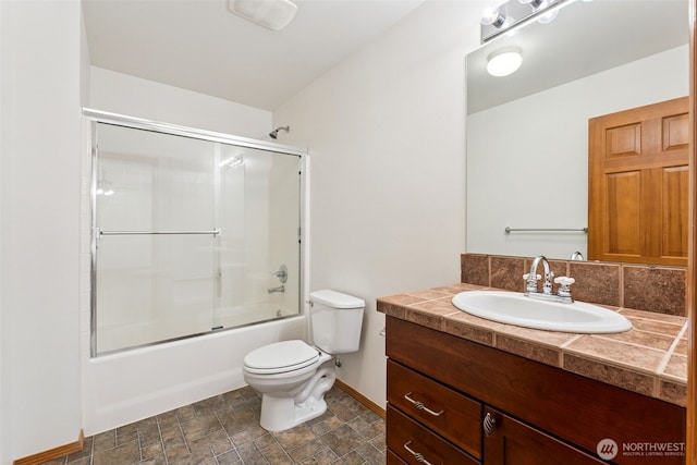 full bath featuring toilet, baseboards, vanity, bath / shower combo with glass door, and stone finish flooring