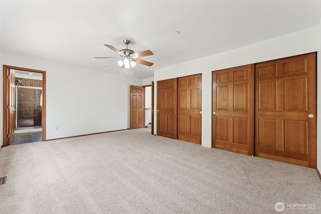 unfurnished bedroom with multiple closets, carpet floors, connected bathroom, baseboards, and a ceiling fan