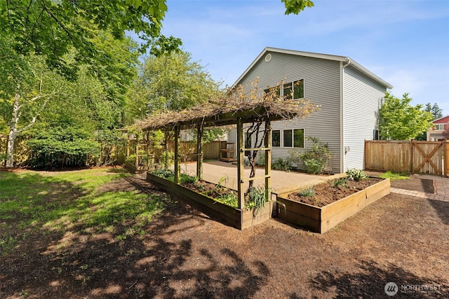 back of property with a vegetable garden, a fenced backyard, a patio, and a pergola