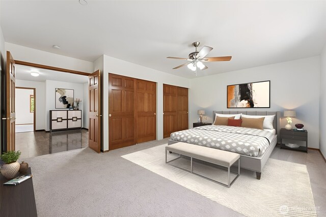 carpeted bedroom with multiple closets and a ceiling fan