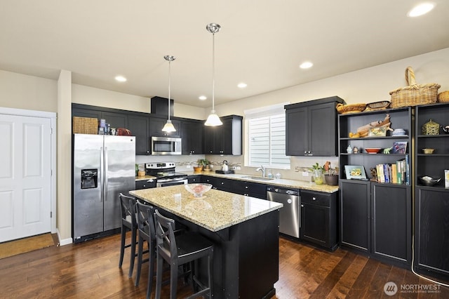 18709 138th Street Ct E, Bonney Lake, WA 98391 - kitchen featuring appliances with stainless steel finishes, light stone countertops, a kitchen island, dark wood-type flooring, and a sink