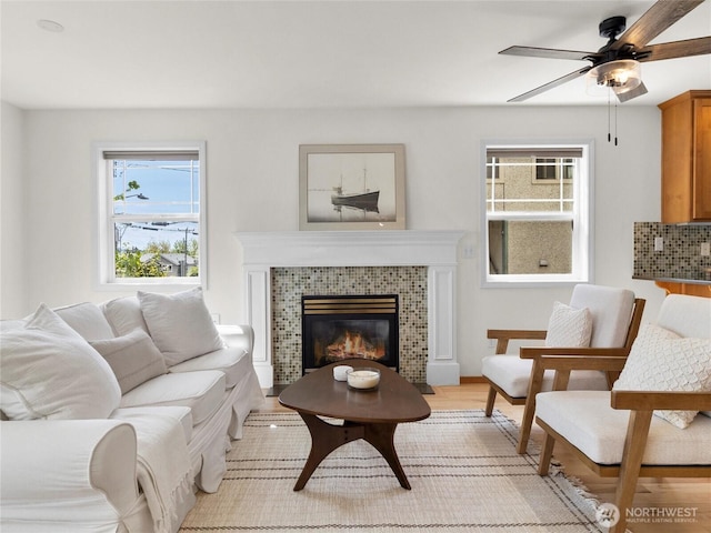 living room featuring a ceiling fan, light wood-style flooring, and a fireplace