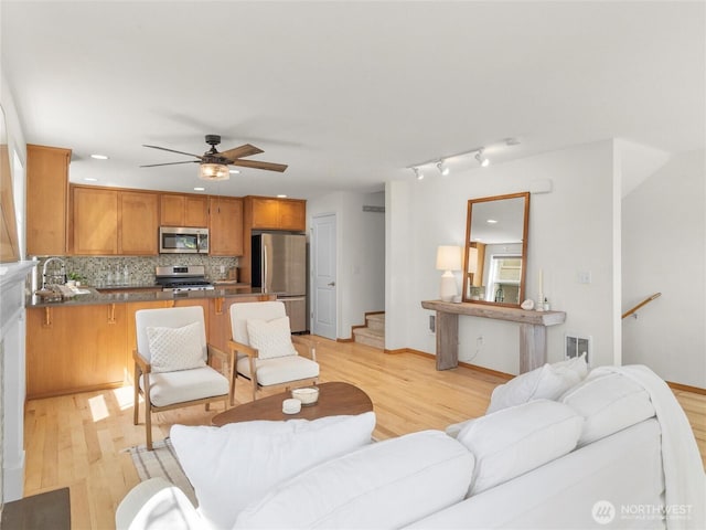 living room with light wood-style flooring, ceiling fan, stairway, baseboards, and recessed lighting