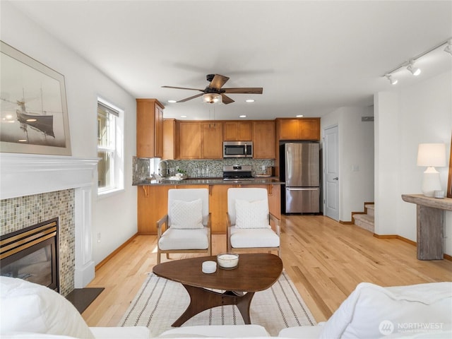 living room featuring light wood-type flooring, a ceiling fan, stairs, baseboards, and recessed lighting