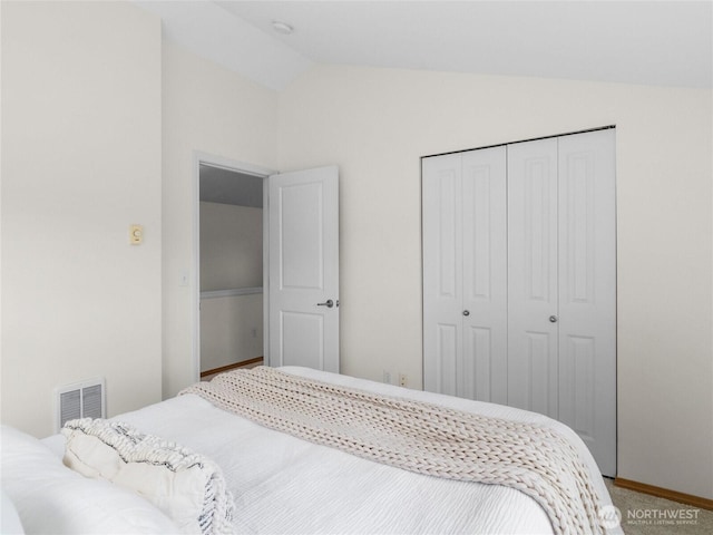 carpeted bedroom featuring vaulted ceiling, a closet, and baseboards