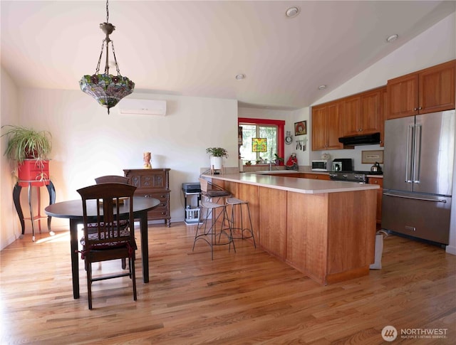 2078 11th St, Port Townsend, WA 98368 - kitchen featuring appliances with stainless steel finishes, brown cabinetry, vaulted ceiling, a peninsula, and light wood-type flooring