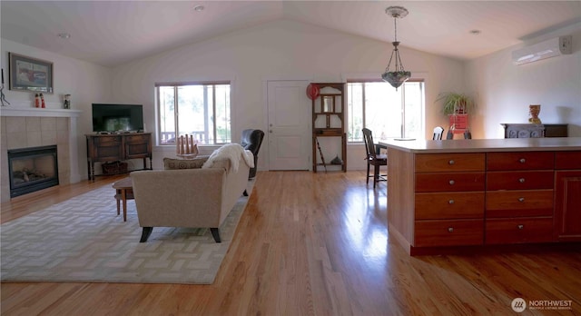 2078 11th St, Port Townsend, WA 98368 - living area featuring healthy amount of natural light, vaulted ceiling, light wood-type flooring, a wall mounted air conditioner, and a tiled fireplace