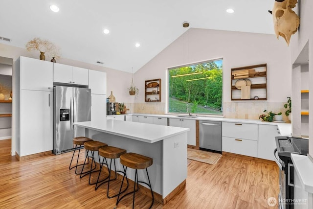 5601 Lewis River Rd, Ariel, WA 98603 - kitchen with stainless steel appliances, a sink, a breakfast bar, white cabinetry, and light wood-type flooring
