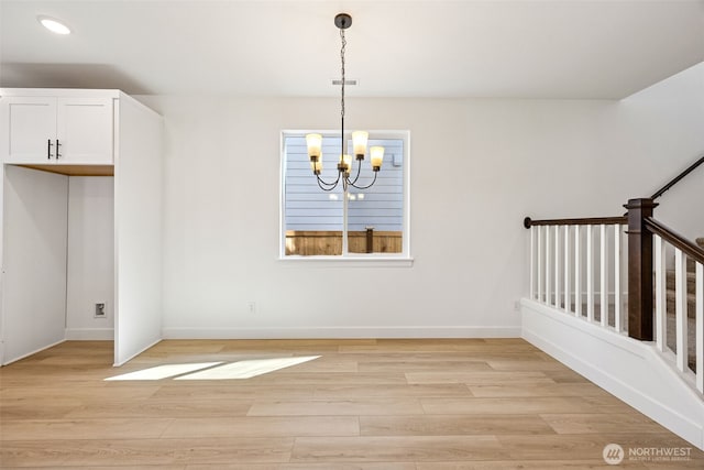 unfurnished dining area featuring light wood-style floors, baseboards, visible vents, and a chandelier