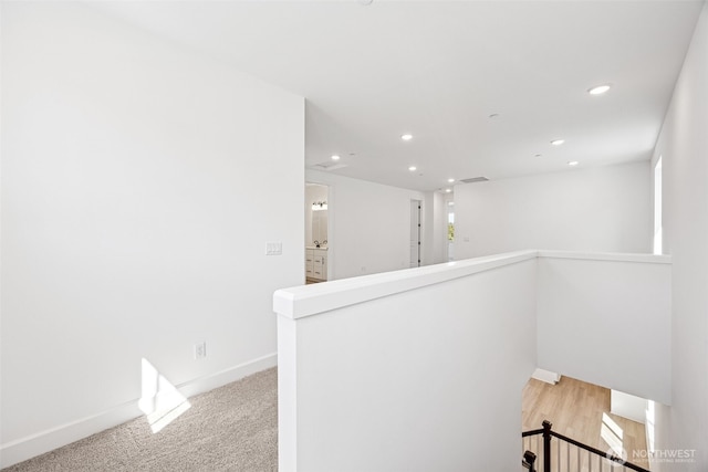 hall with baseboards, recessed lighting, and an upstairs landing