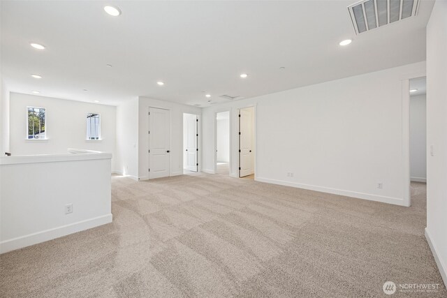 unfurnished room with baseboards, light colored carpet, recessed lighting, and visible vents