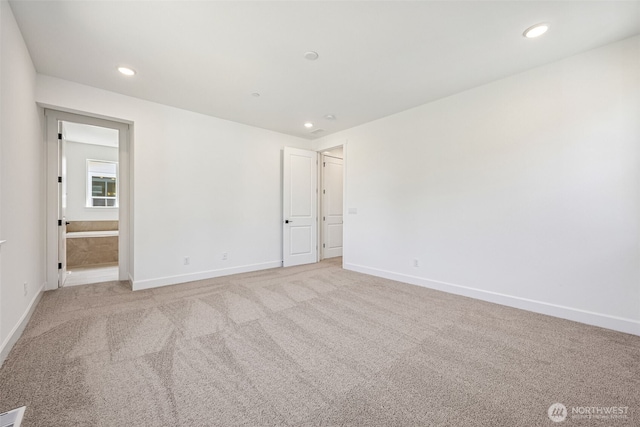 unfurnished bedroom with baseboards, recessed lighting, ensuite bath, and light colored carpet