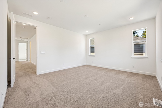 empty room with light colored carpet, visible vents, and a wealth of natural light