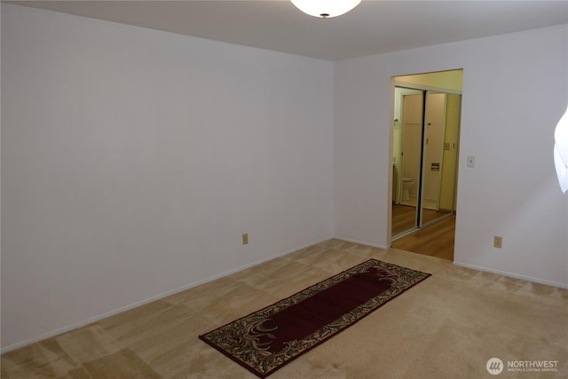 spare room featuring baseboards and light colored carpet