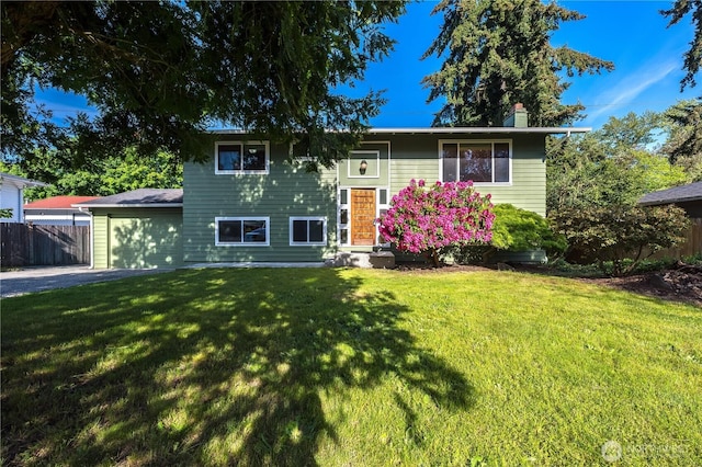 bi-level home with driveway, an attached garage, and a chimney