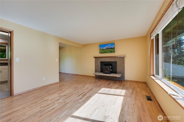 unfurnished living room with light wood finished floors and a brick fireplace