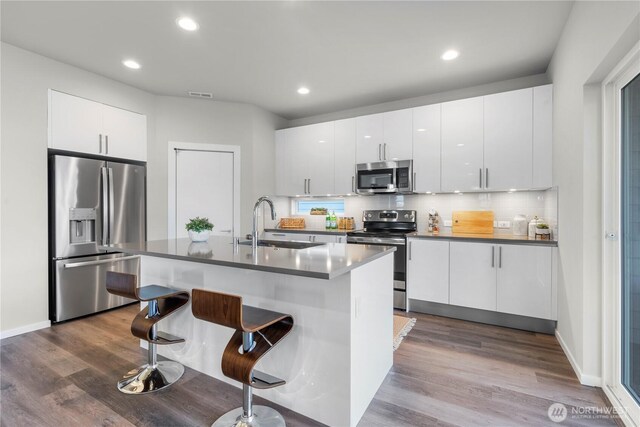 13826 Brookdale Ln E Unit 96, Tacoma, WA 98445 - kitchen with a breakfast bar, dark wood-style floors, recessed lighting, a sink, and appliances with stainless steel finishes