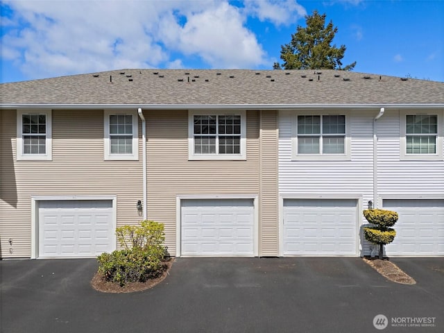 exterior space with a garage, roof with shingles, and driveway