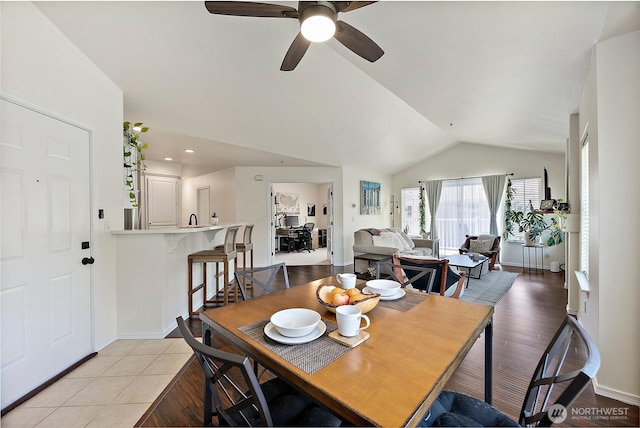 dining area with baseboards, a ceiling fan, light wood-style flooring, and lofted ceiling