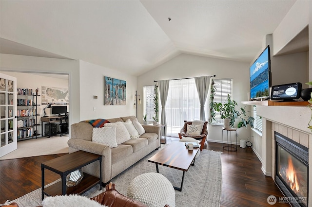 living area featuring baseboards, a fireplace, vaulted ceiling, and wood finished floors