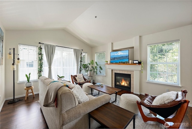 living area with a tiled fireplace, lofted ceiling, dark wood-style flooring, and a wealth of natural light