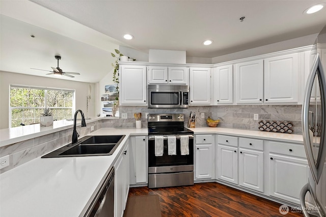 kitchen featuring a ceiling fan, dark wood-style flooring, a sink, white cabinets, and stainless steel appliances