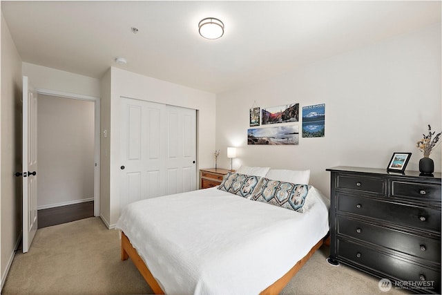 bedroom with a closet, baseboards, and light carpet
