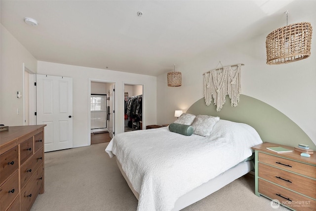 bedroom featuring a closet, a walk in closet, light carpet, and ensuite bathroom