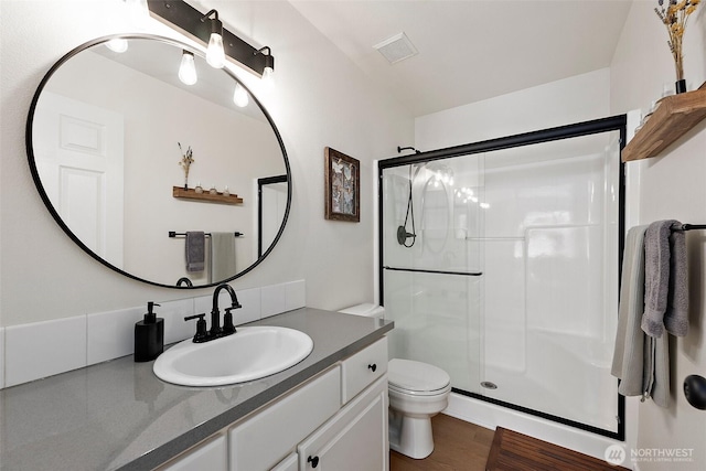 bathroom with vanity, a stall shower, toilet, and visible vents