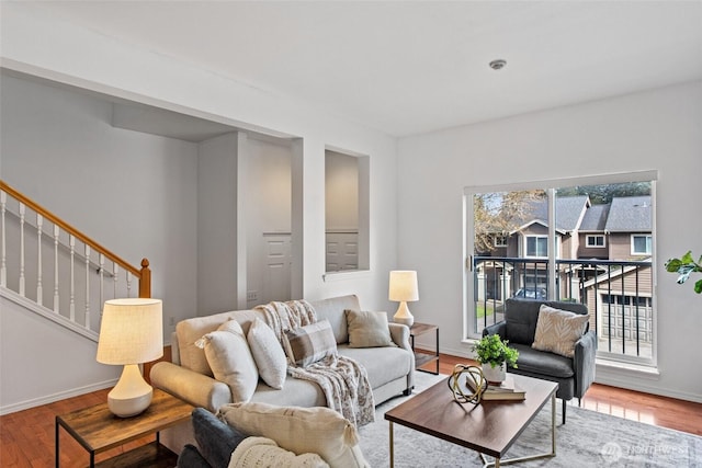 living room featuring baseboards, wood finished floors, and stairway
