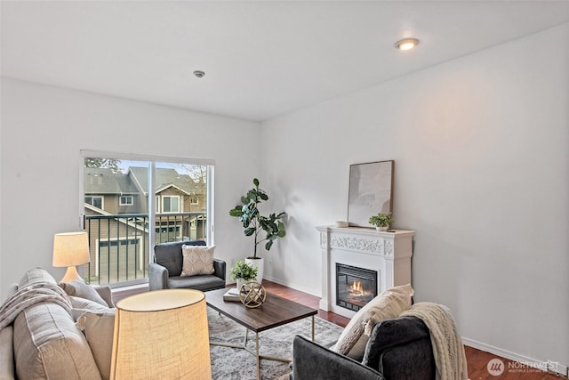 living room with baseboards, a glass covered fireplace, and wood finished floors