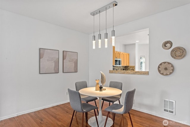 dining area with visible vents, baseboards, and wood finished floors