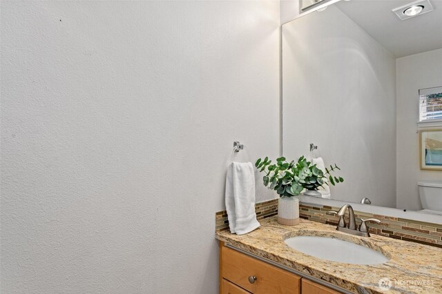 bathroom with vanity, decorative backsplash, and toilet