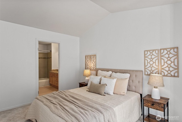 bedroom featuring ensuite bathroom, vaulted ceiling, and light colored carpet