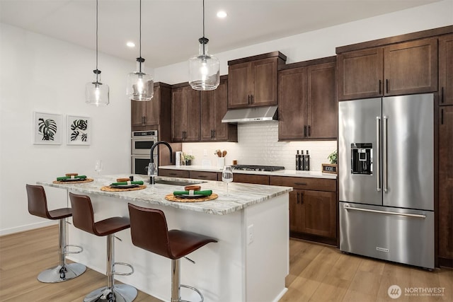 33107SITE142 Liberty Ave SE, Black Diamond, WA 98010 - kitchen with appliances with stainless steel finishes, under cabinet range hood, light wood-style flooring, a sink, and recessed lighting