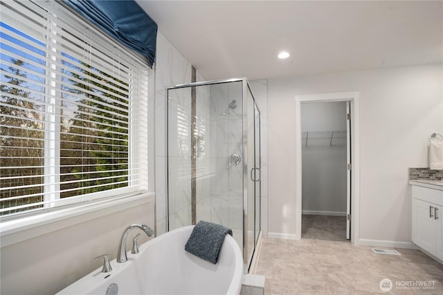 bathroom featuring visible vents, a soaking tub, a spacious closet, and a shower stall