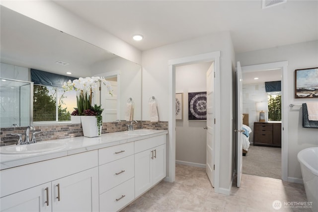 ensuite bathroom with a sink, decorative backsplash, ensuite bath, and double vanity