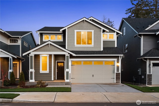 craftsman house with an attached garage, driveway, and stone siding