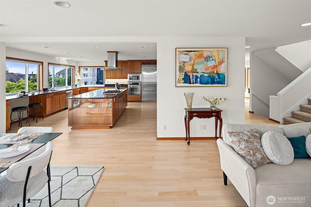 living room featuring recessed lighting, light wood-style flooring, baseboards, and stairway