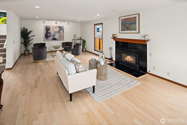 living room with light wood-style floors, stairs, recessed lighting, a tile fireplace, and baseboards