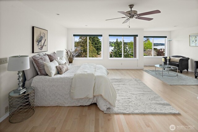 bedroom with multiple windows, wood finished floors, baseboards, and a ceiling fan