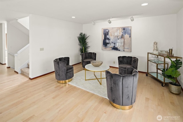 sitting room featuring wood finished floors, track lighting, stairs, baseboards, and recessed lighting