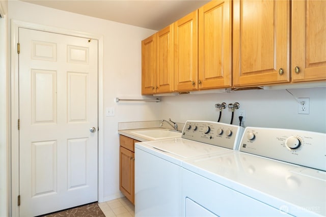 washroom with cabinet space, baseboards, washer and clothes dryer, and a sink