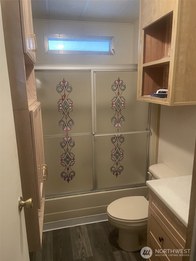 bathroom with toilet, wood finished floors, bath / shower combo with glass door, and vanity