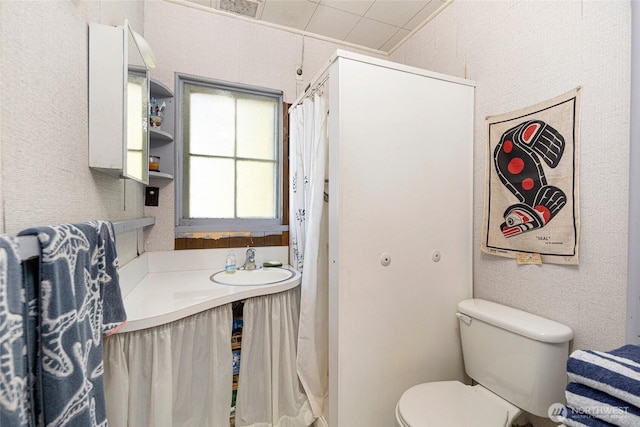 full bathroom featuring a sink, a shower with shower curtain, toilet, and visible vents