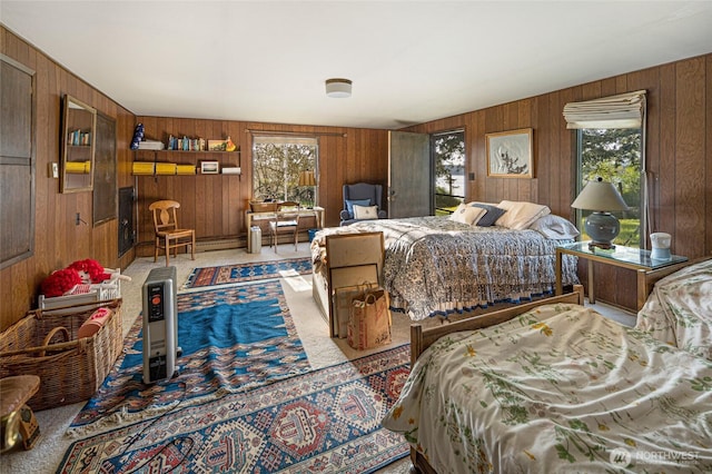 bedroom with a baseboard heating unit, wood walls, and carpet